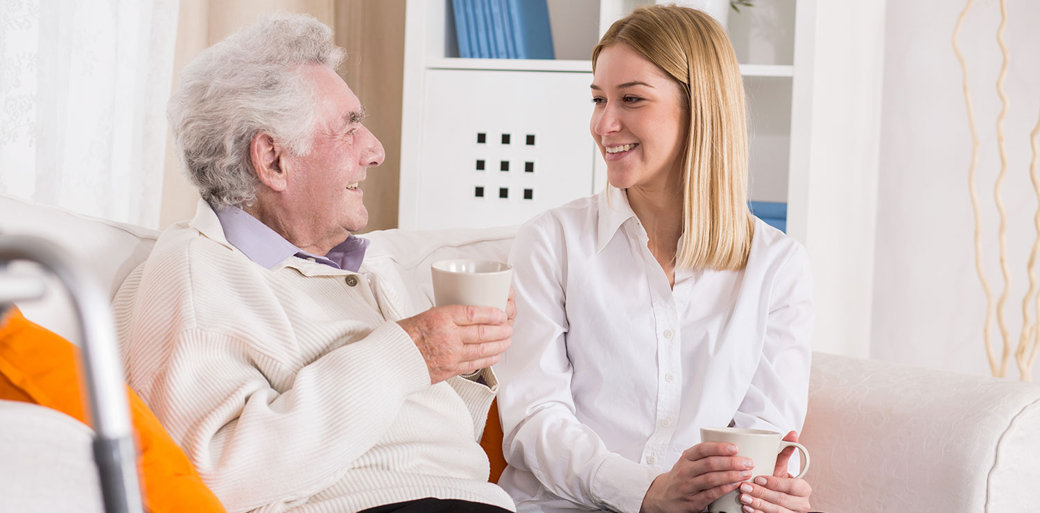 Grandfather and granddaughter smiling, talking and drinking tea